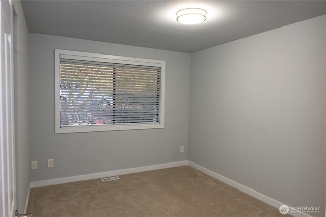 spare room featuring carpet, visible vents, and baseboards