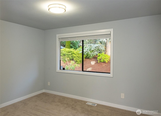 spare room featuring carpet floors, visible vents, and baseboards