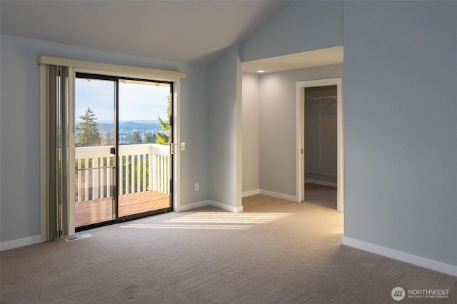 carpeted empty room with vaulted ceiling, visible vents, and baseboards