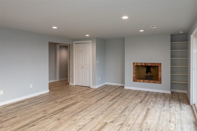 unfurnished living room with baseboards, a brick fireplace, wood finished floors, and recessed lighting