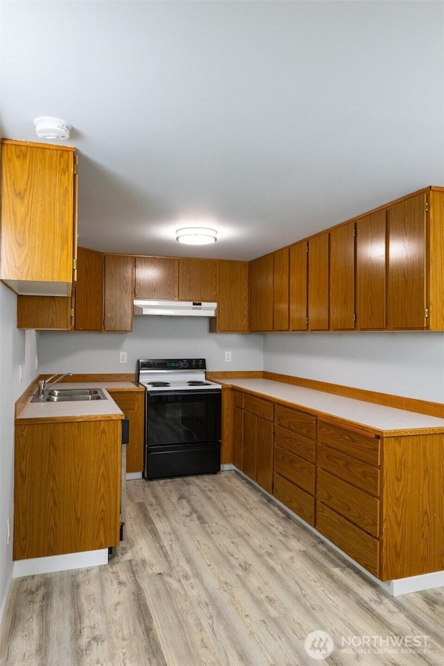 kitchen with brown cabinets, range with electric stovetop, light wood-style flooring, a sink, and under cabinet range hood