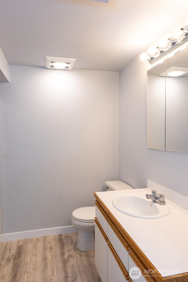 bathroom featuring baseboards, visible vents, toilet, wood finished floors, and vanity