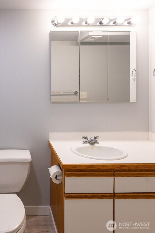 bathroom with toilet, baseboards, wood finished floors, and vanity