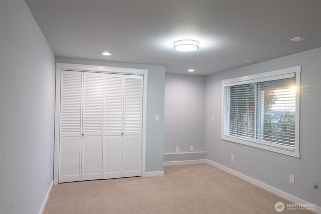 unfurnished bedroom with recessed lighting, baseboards, a closet, and light colored carpet