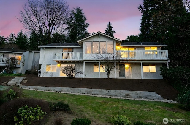 rear view of property with a yard and a balcony