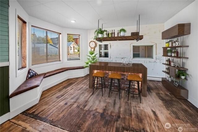 dining room featuring a baseboard heating unit, wood finished floors, and baseboards