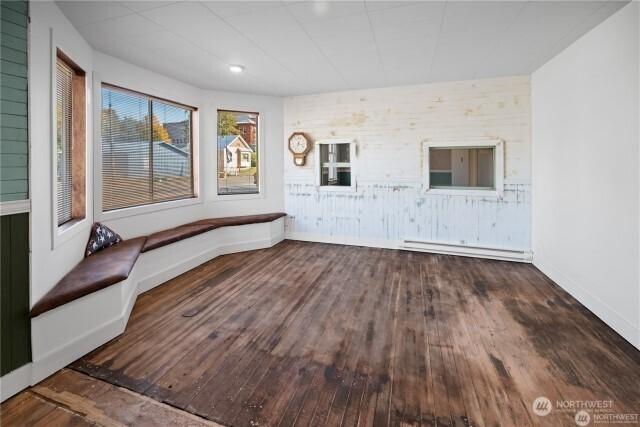 spare room featuring baseboards, a baseboard heating unit, and wood finished floors