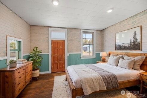 bedroom featuring a wainscoted wall and wood finished floors