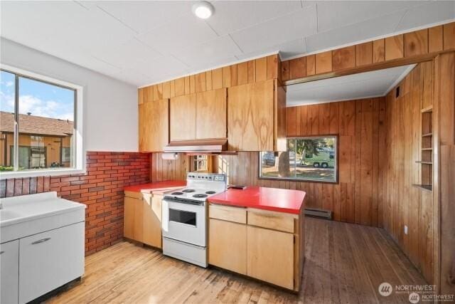 kitchen with white electric range oven, wooden walls, under cabinet range hood, and light wood-style floors