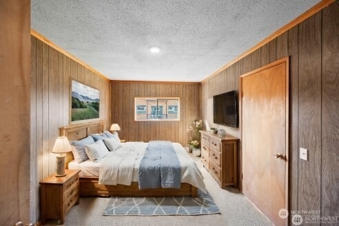 bedroom featuring a textured ceiling, carpet floors, and wooden walls