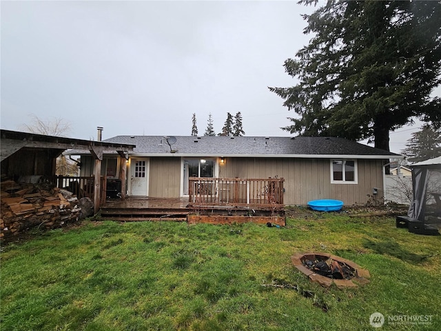 rear view of house with an outdoor fire pit, a yard, and a wooden deck