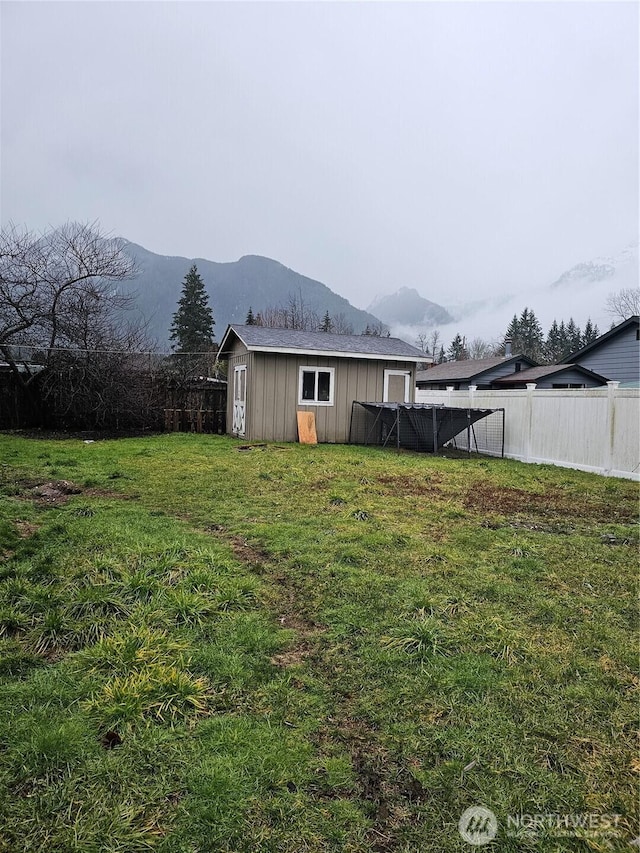 view of yard with an outbuilding, a shed, a fenced backyard, and a mountain view