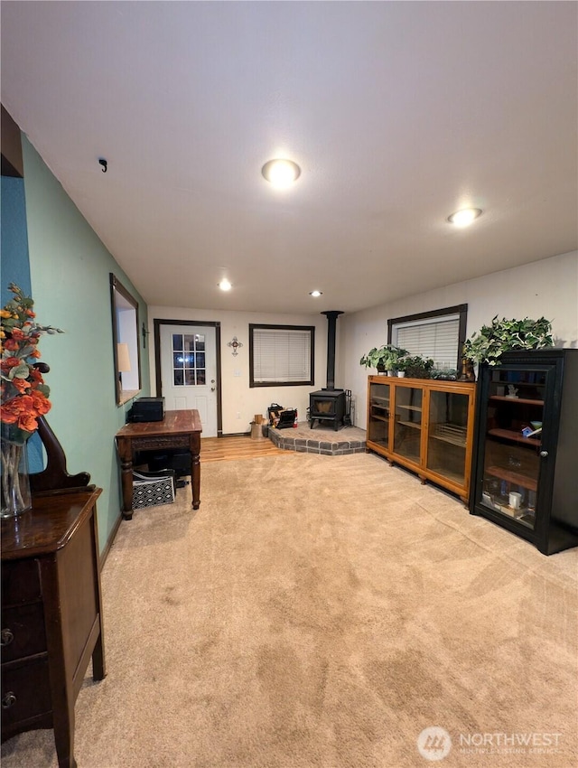 carpeted living area featuring recessed lighting and a wood stove