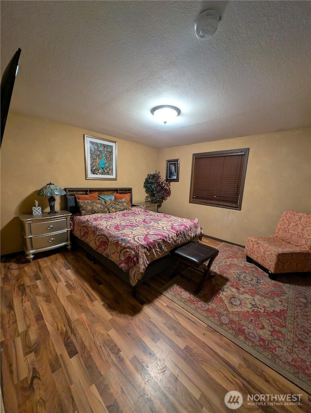 bedroom with a textured ceiling and wood finished floors