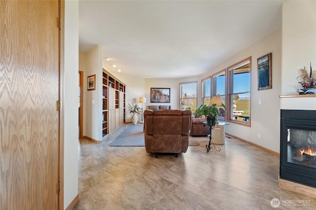 living room featuring a multi sided fireplace and baseboards