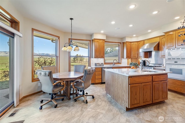 kitchen with white appliances, light countertops, wall chimney exhaust hood, and a sink