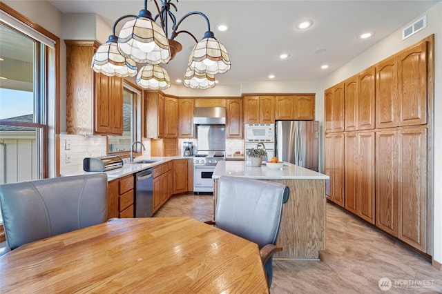 kitchen with visible vents, a sink, a kitchen island, stainless steel appliances, and light countertops