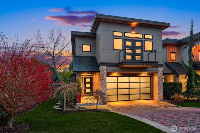 contemporary home featuring a garage, metal roof, and decorative driveway