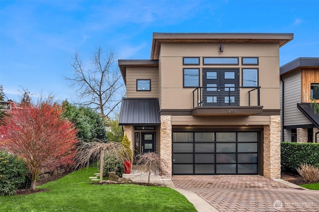 contemporary home featuring decorative driveway, a balcony, an attached garage, and stucco siding