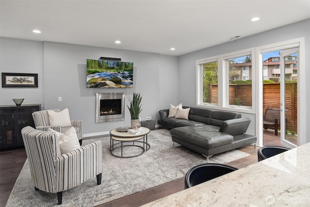 living room with recessed lighting, a lit fireplace, baseboards, and wood finished floors