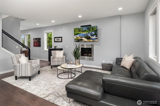 living room with recessed lighting, a lit fireplace, baseboards, and wood finished floors