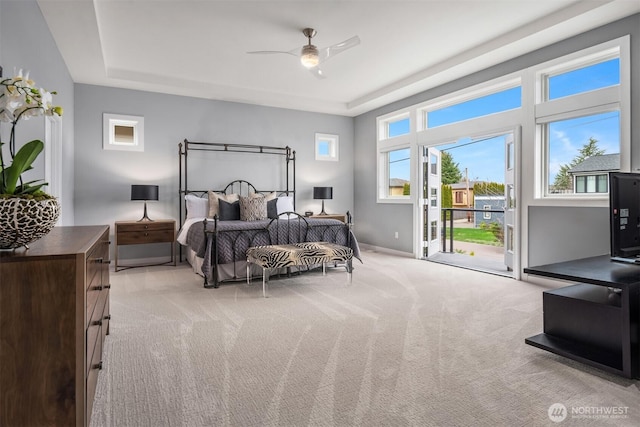 bedroom with baseboards, a raised ceiling, light colored carpet, ceiling fan, and access to exterior