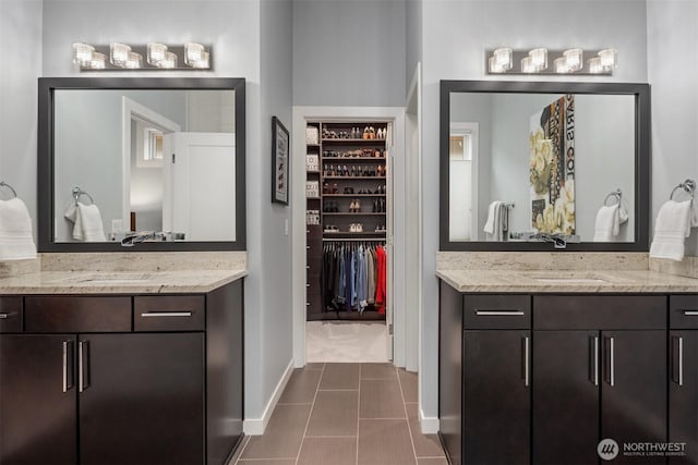 full bathroom with tile patterned flooring, baseboards, two vanities, and a sink