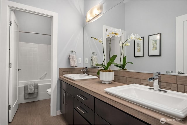 full bath with washtub / shower combination, double vanity, a sink, and toilet