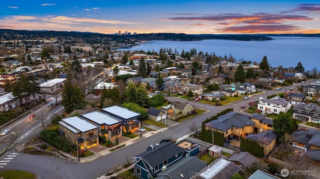 aerial view at dusk featuring a water view and a residential view