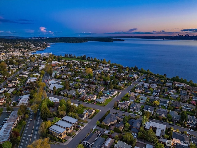 aerial view at dusk featuring a water view and a residential view