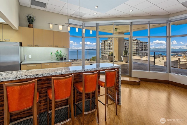 2821 2nd Ave Unit 1005, Seattle, WA 98121 - kitchen featuring a kitchen breakfast bar, light wood-type flooring, a water view, stainless steel fridge, and baseboards