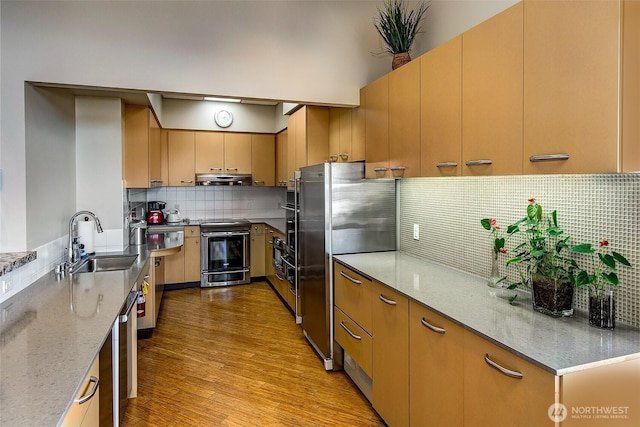 2821 2nd Ave Unit 1005, Seattle, WA 98121 - kitchen with light wood-type flooring, under cabinet range hood, decorative backsplash, stainless steel appliances, and a sink