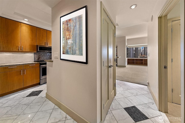 2821 2nd Ave Unit 1005, Seattle, WA 98121 - kitchen featuring brown cabinetry, baseboards, appliances with stainless steel finishes, and marble finish floor
