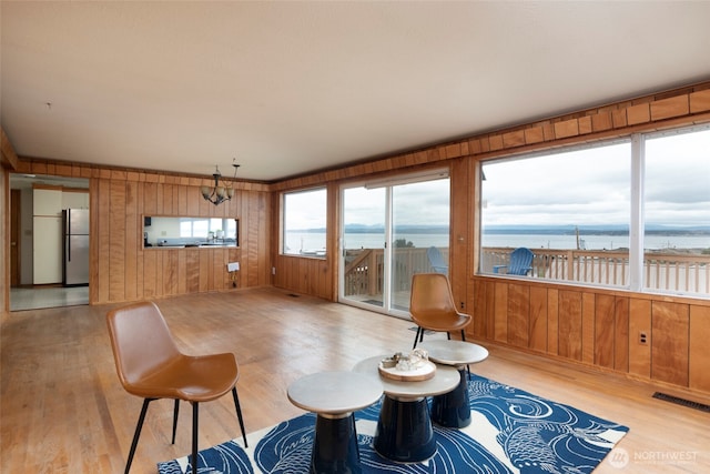 interior space with a water view, wood finished floors, visible vents, and wood walls