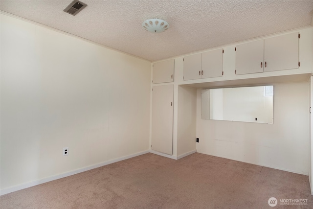 unfurnished room featuring light carpet, visible vents, a textured ceiling, and baseboards