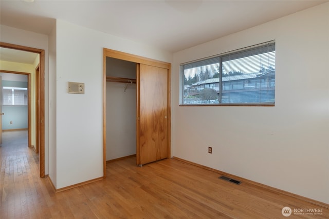 unfurnished bedroom featuring visible vents, baseboards, light wood-style floors, and a closet