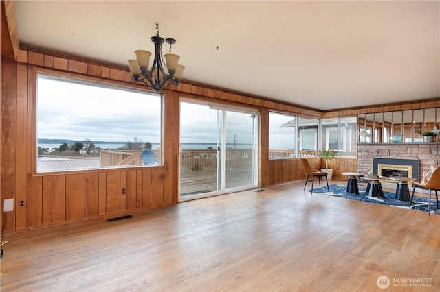 living area featuring visible vents, a notable chandelier, wood finished floors, wooden walls, and a fireplace