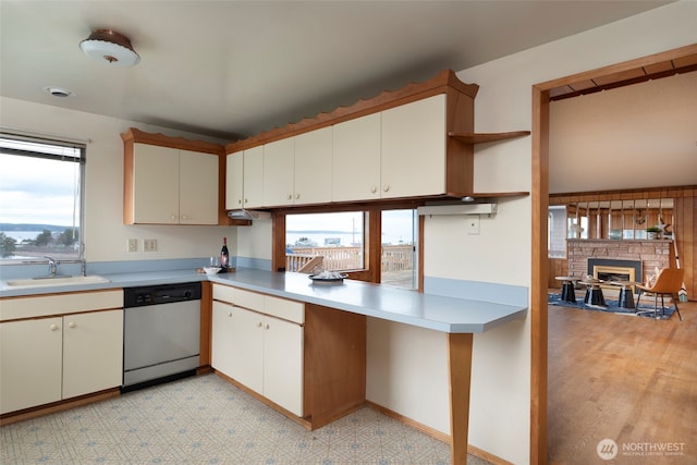 kitchen featuring open shelves, light floors, dishwasher, light countertops, and a sink