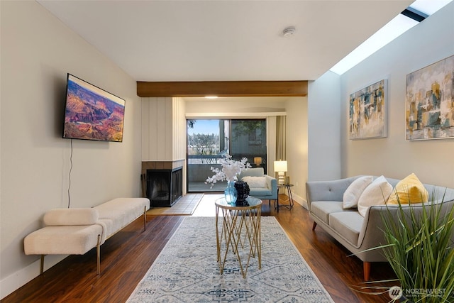 living area with beam ceiling, baseboards, dark wood-type flooring, and a multi sided fireplace