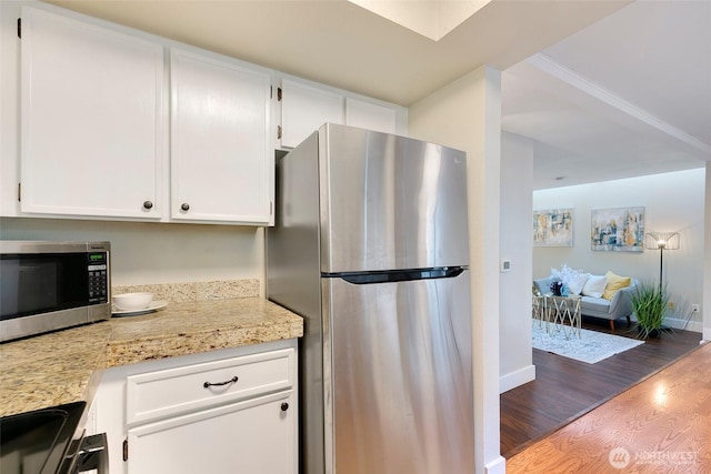 kitchen with wood finished floors, white cabinetry, baseboards, appliances with stainless steel finishes, and light stone countertops