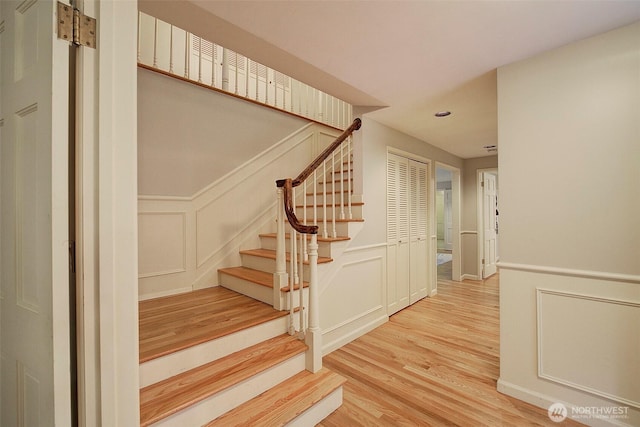 stairs featuring a decorative wall and wood finished floors