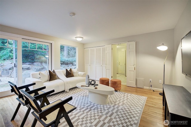 living area featuring baseboards and light wood finished floors