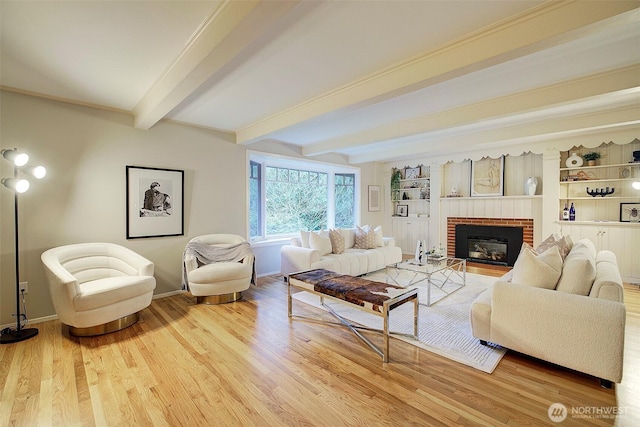 living room featuring light wood-type flooring, a fireplace, beamed ceiling, and baseboards