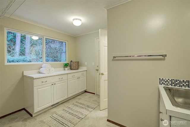 interior space with crown molding, baseboards, and a sink