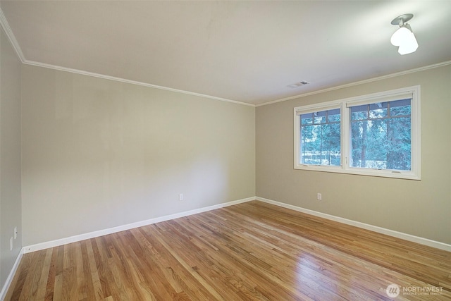 empty room with visible vents, crown molding, light wood-style flooring, and baseboards