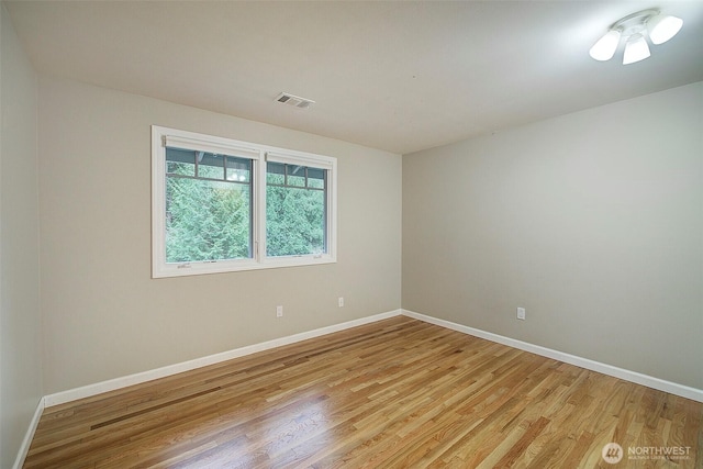 empty room with visible vents, light wood-style flooring, and baseboards