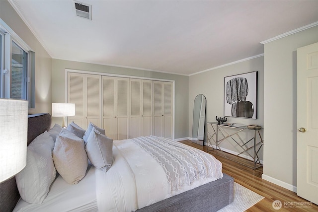 bedroom featuring baseboards, crown molding, visible vents, and wood finished floors