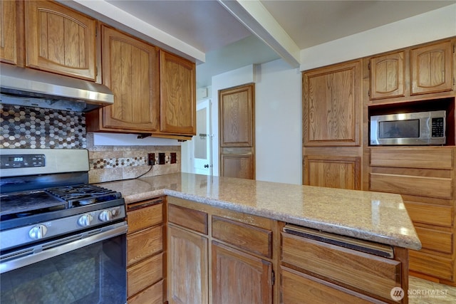 kitchen with backsplash, under cabinet range hood, light stone counters, a peninsula, and stainless steel appliances