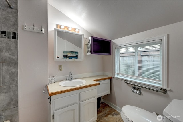 bathroom with baseboards, toilet, vanity, and lofted ceiling