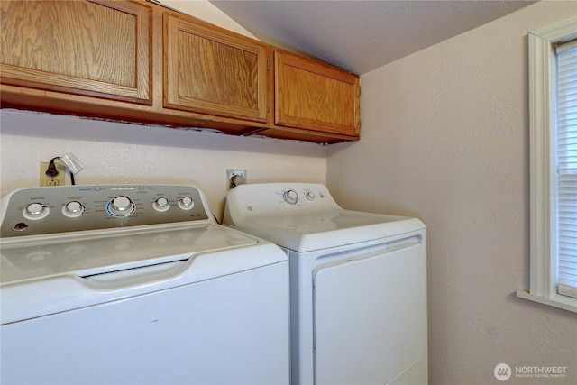 laundry room featuring cabinet space, a textured wall, and separate washer and dryer